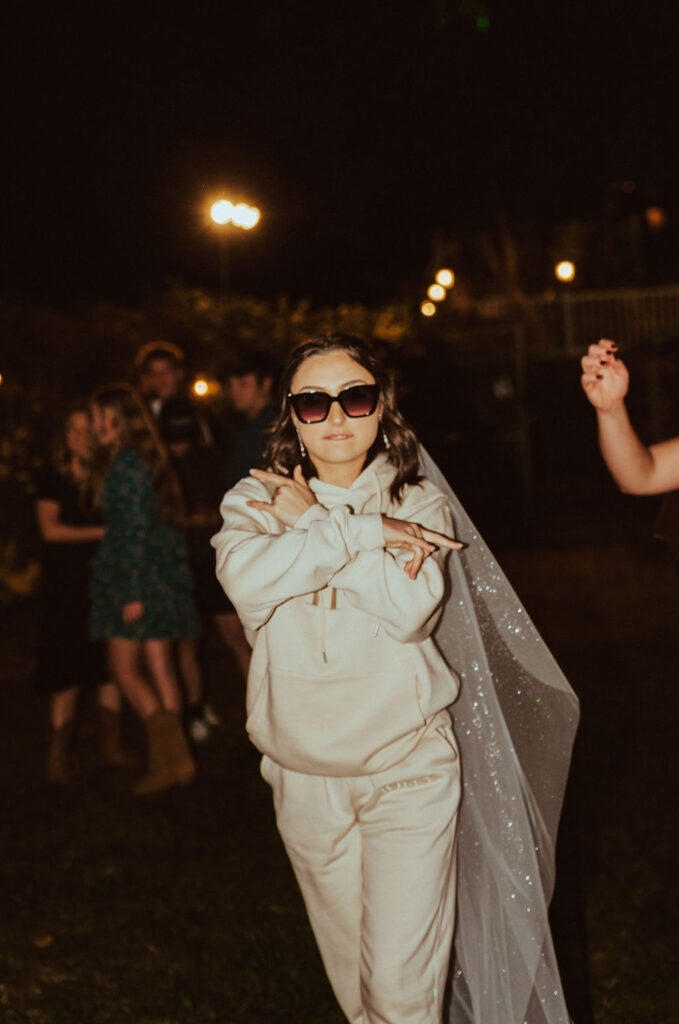 bride dancing during the reception in her bride sweat suit and wedding veil 