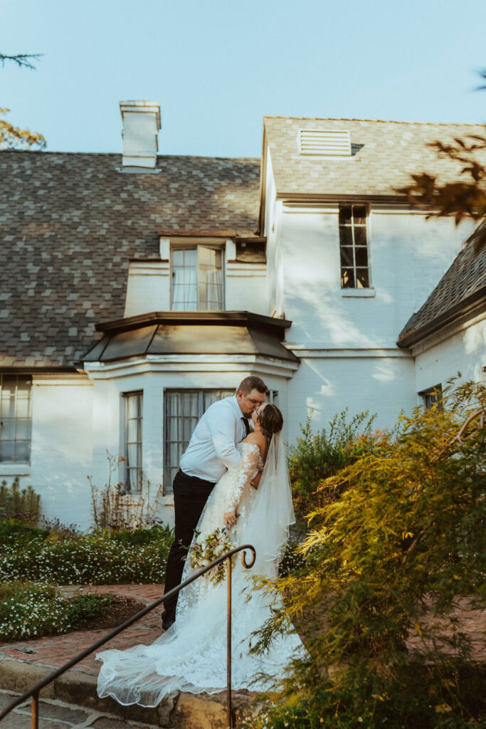 bride and groom kissing infront of country building