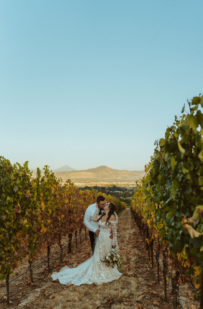 bride and groom kissing in vineyard