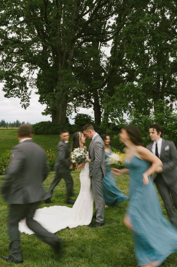 bride and groom kissing while bridal party move around them.